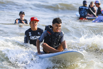 Young men sitting on surf boards in the ocean.