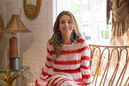 Close-up portrait of Joey Wölffer smiling in a striped sweater sitting indoors.