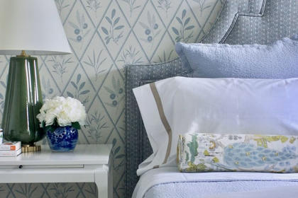 Centered view of a fully made bed with a rounded upholstered headboard, decorative throw pillows, matching nightstands, and a upholstered bench at the foot of the bed.