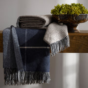 Navy and grey Benito fringed throws folded on a wooden console table