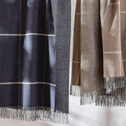 Close-up of hanging Benito windowpane throws in navy and tan with fringe