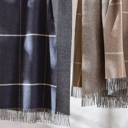 Close-up of hanging Benito windowpane throws in navy and tan with fringe