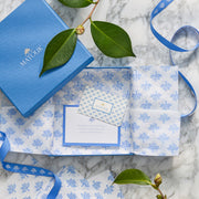 Matouk gift card in a blue gift box with patterned tissue paper, green leaves and blue ribbon