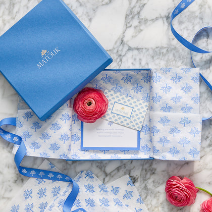Matouk gift card in a blue gift box with patterned tissue paper and pink ranunculus