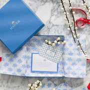 Matouk gift card in a blue gift box with patterned tissue paper and winter berry sprigs