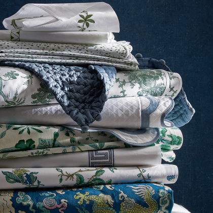 Stack of Schumacher x Matouk floral, quilted, and chinoiserie bedding prints.