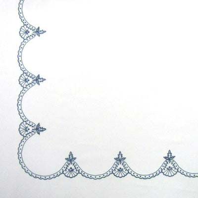 Close up of a napkin featuring a delicate navy blue scalloped border design along the left and bottom edges.