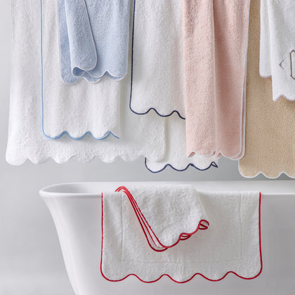 White Cairo Scallop towels with colorful scalloped edges, hanging above and draped over a tub.