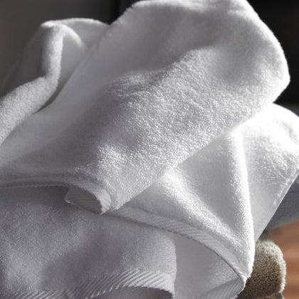 White Milagro bath towels folded and stacked, close-up