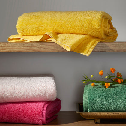 Milagro bath towels in yellow, pink, and green on open shelves