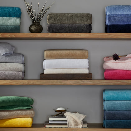 Milagro bath towels displayed in a full range of colors on shelves