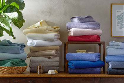 Milagro towels stacked in an array of colors on a console