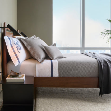 Gray Alba textured pique bedding with a monogrammed sham, styled on a bed near a window.
