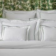 Ansonia white shams with green satin-stitch border on a bed