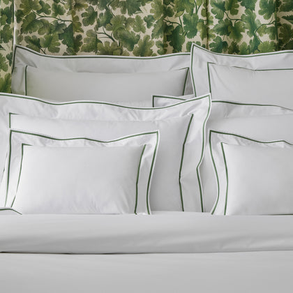 Ansonia white shams with green satin-stitch border on a bed
