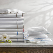 Ansonia white sheets stacked with multicolor satin-stitch borders