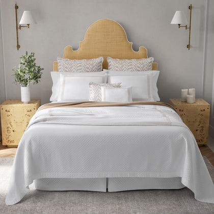 White Astor Braid quilted bedding with tan zebra-print pillows, styled on a bed with a rattan headboard.