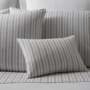 Calypso pinstripe bedding in taupe, shams and a sheet on a bed