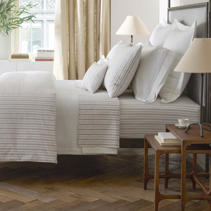 Calypso tan striped bedding styled on a bed in a bedroom.