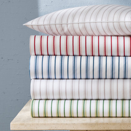 White Calypso striped sheets in assorted colors, stacked with a matching pillow.
