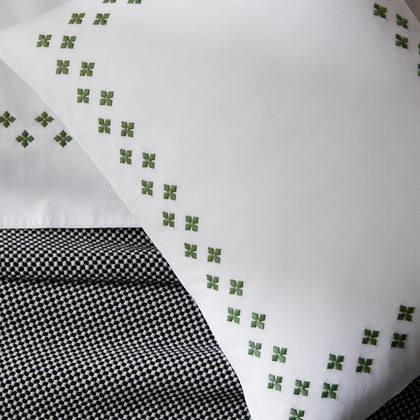 Casablanca Clover white pillow shams styled on a bed with patterned throw.