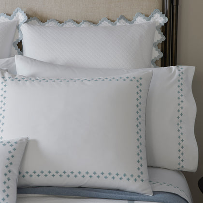 Casablanca pillows with blue cross-stitch trim and scalloped sham edge.