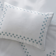 Casablanca white pillow with blue embroidered border styled on a bed.
