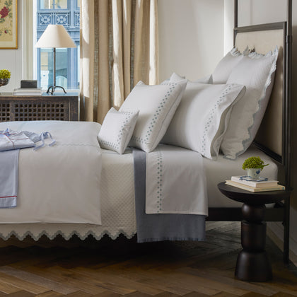 Casablanca white bedding styled on a bed with folded pajamas nearby.