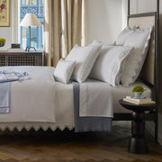 Casablanca white bedding styled on a bed with folded pajamas nearby.