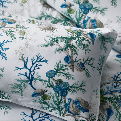 Close-up of a blue and green Del Tesoro coral and shell print pillow.