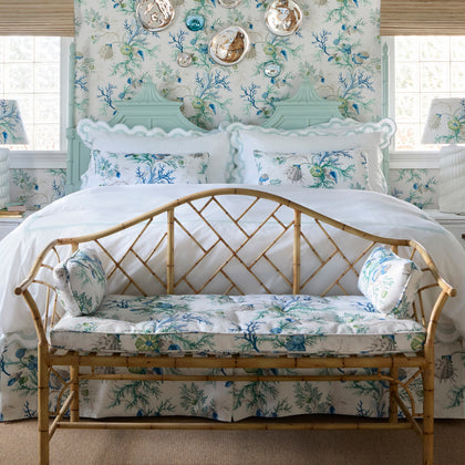 Blue Del Tesoro coral and shell print bedding with a matching bamboo bench cushion, in a bedroom with matching wallpaper.
