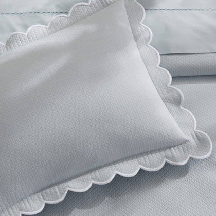 Close-up of a light gray-blue diamond-textured DiamondPique sham with a white scalloped edge.