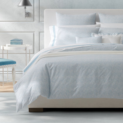 Pale blue Duma Diamond print bedding styled on a white upholstered bed.
