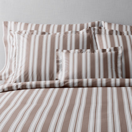 Taupe and white striped pillow shams layered on matching striped bedding.