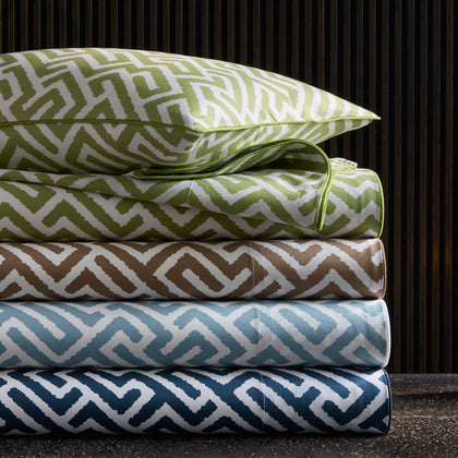 Gabriel geometric print sheets in green, brown, blue, and navy, stacked against wood slats.