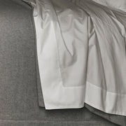 Gatsby white percale sheet with a hemstitch border, draped on a headboard