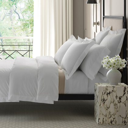 White Gatsby Hemstitch bedding styled on a bed near a balcony window.