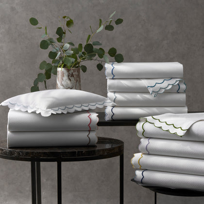White India Pique scalloped sheets stacked with colorful trim, near a eucalyptus plant.