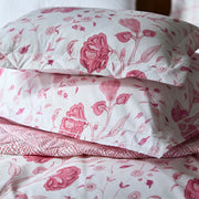 Close-up of a quilted pink floral pillow sham and sheet with a tulip and daisy print, over a pink dotted fabric.