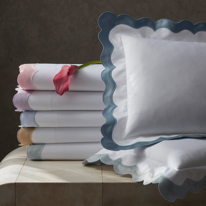 White Lorelei scalloped sheets in colorful trim, stacked with a pink calla lily.