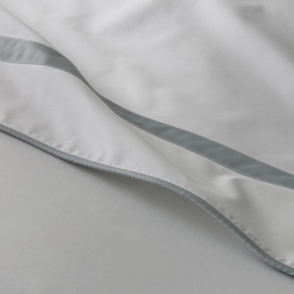 Close-up of white Louise sheets with a light gray ribbon trim.
