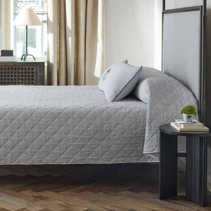 Matteo quilted coverlet in deep navy stripe on a bed.