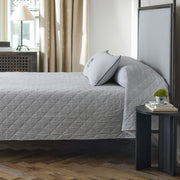 Matteo deep navy quilted coverlet styled on a bed in a bedroom.