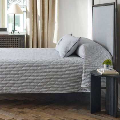 Matteo deep navy quilted coverlet styled on a bed in a bedroom.