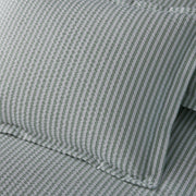 Close-up of sage green-striped Matteo seersucker pillow and sheets.