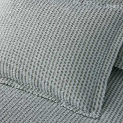 Close-up of sage green-striped Matteo seersucker pillow and sheets.