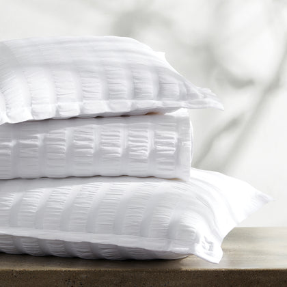 White Panama seersucker-textured pillows stacked on a marble table.