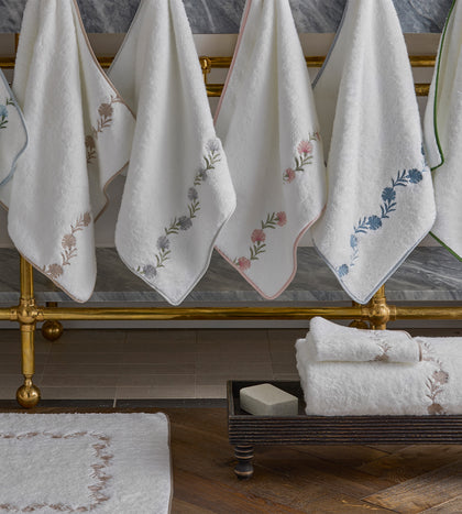 White Daphne towels with an embroidered floral vine trim, hanging.