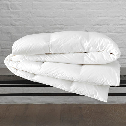 White Chalet down comforter folded on a metal bench frame.