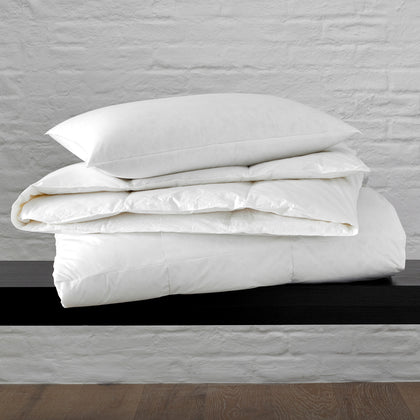 White Montreux down comforter folded on a black bench.